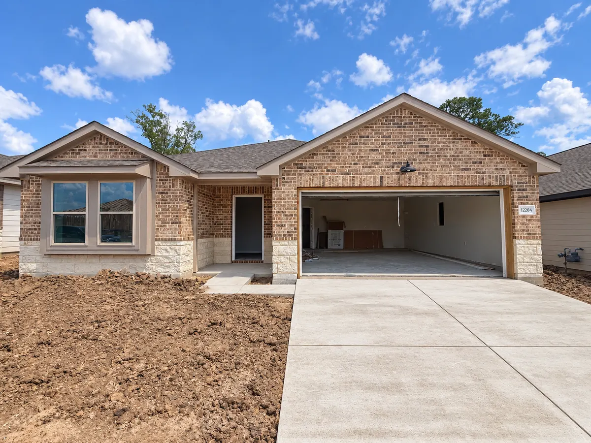 Brick Sonoma home during construction at 12204 Lexington Heights Drive, with an open garage and digitally cleaned concrete driveway