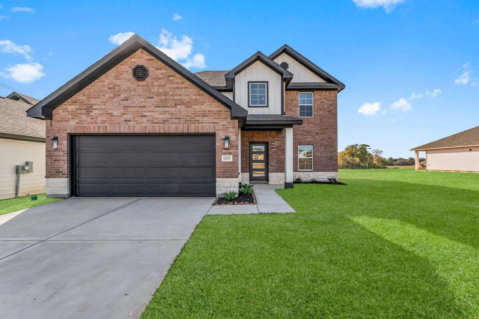 Two-story brick home with a black garage door and covered front entry
