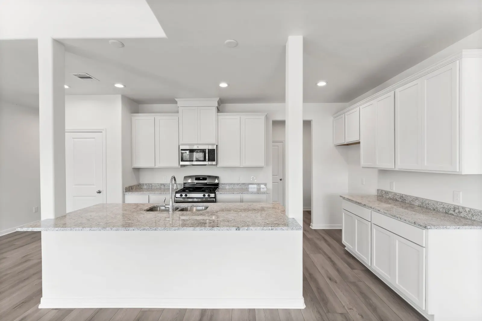 White kitchen with a granite breakfast bar and wood-look flooring